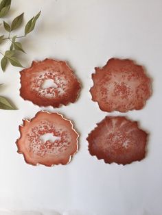 four pieces of pink agate glass sitting on top of a white surface next to a plant