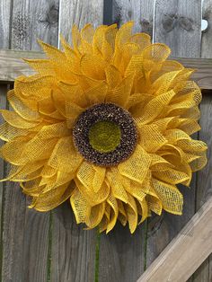 a large yellow sunflower sitting on top of a wooden fence