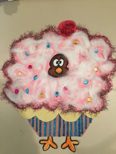 a pink cupcake decorated with sprinkles and a bird