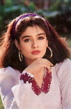 a woman with long hair wearing large hoop earrings and a white shirt is posing for a photo