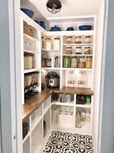 a kitchen pantry with white cabinets and wooden counter tops, black and white tile flooring