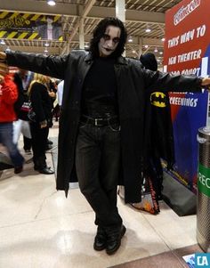 a man dressed up as the joker in a convention hall with his arms spread out