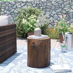 a wooden table sitting on top of a patio next to a stone wall and flowers