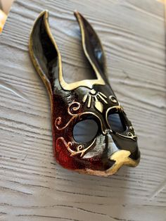 a black and gold mask sitting on top of a wooden table