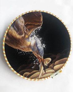 a plate with an image of a bird on it's side and water splashing from its beak