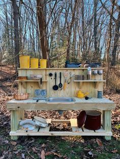 an outdoor kitchen in the woods with pots and pans