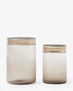 two glass jars with gold lids are shown on a white background, one is empty and the other has a metal lid