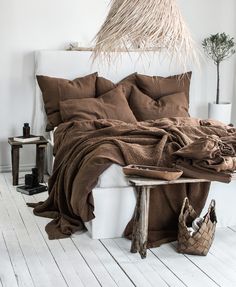 a bed covered in brown linens and pillows with a basket on the end table next to it