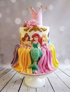 there is a multi layer cake with princesses on it