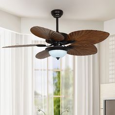 a ceiling fan that is hanging from the ceiling in front of a window with curtains