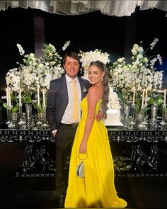 a man and woman standing next to each other in front of a table with flowers