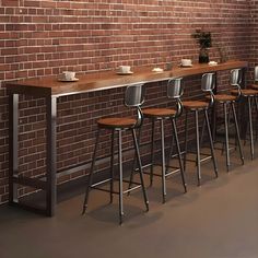 a bar with four stools in front of a brick wall