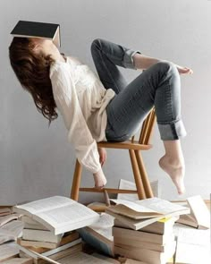 a woman laying on top of a wooden chair next to stacks of books and an open book