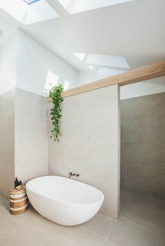 a large white bathtub sitting under a skylight in a bathroom next to a toilet