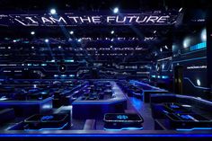 a large room filled with lots of black tables and blue lights on the ceiling is lit up