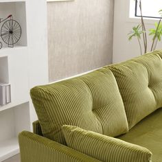 a green couch sitting in front of a book shelf