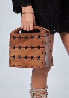 a woman is holding a wooden box with black crosses on it and laces around the bottom