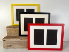 three different colored frames sitting next to each other on top of a wooden block,