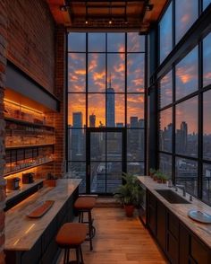 an open kitchen with lots of windows overlooking the city at sunset or sunrise, and bar stools are on the counter