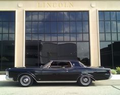 an old black car parked in front of a building