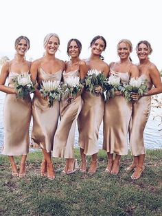 a group of women standing next to each other on top of a grass covered field