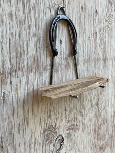 a pair of scissors hanging from a hook on a wooden wall with hooks attached to it