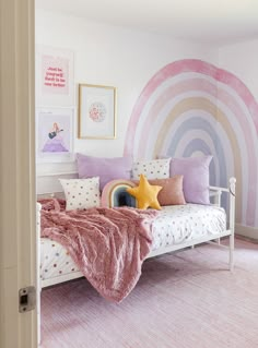 a pink and white bedroom with a rainbow wall mural