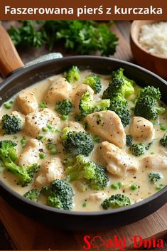 a skillet filled with chicken and broccoli on top of a wooden table