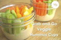 two small glass jars filled with vegetables on top of a wooden table next to the words grab and go veggie hummus cups