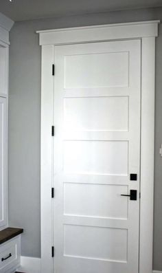 a white door in the corner of a room with gray walls and wood flooring