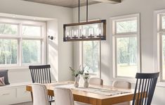 a dining room table with four chairs and a bench in front of two large windows