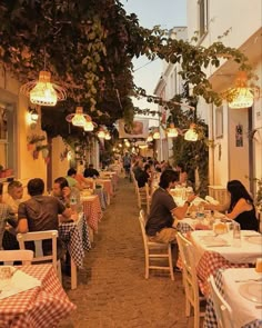 people are sitting at tables in an outdoor dining area with checkered tablecloths