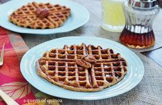 two plates with waffles and syrup on them sitting on a table next to utensils