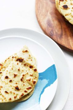 two flat breads on a white plate next to a cutting board with a blue spatula