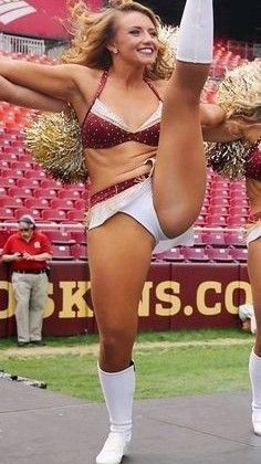 two women in cheerleader outfits are doing tricks on the stage at a football game