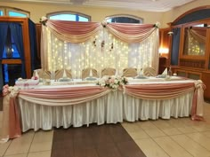 a table set up for a wedding reception with pink and white flowers on the table