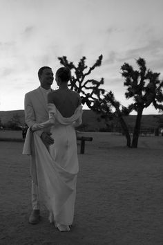 a man and woman standing next to each other in front of a tree with no leaves on it