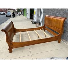 a wooden bed frame sitting on top of a sidewalk