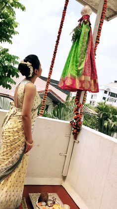 a woman in a sari standing on a balcony next to a tray of food