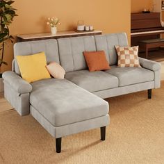 a living room with a gray couch and some pillows on the floor in front of a piano