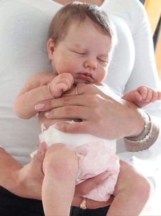 a woman holding a baby in her arms while she is being held by another person