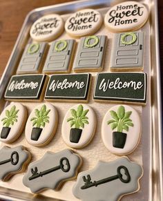 decorated cookies in the shape of keys and house plants on a tray with welcome home stickers