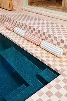 two lounge chairs sitting on the edge of a swimming pool