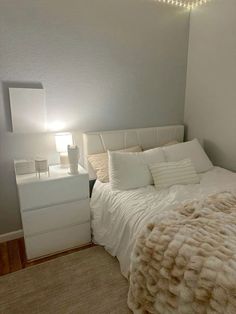 a bedroom with a bed, night stand and lamp in the corner next to it