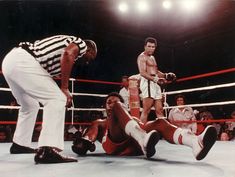 two men in the ring with referee and referee looking at one man laying on the ground