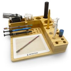 an assortment of pens, pencils and other office supplies in a wooden holder on a white background