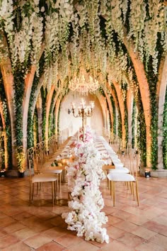 a long table with white flowers and greenery on the walls is set up for a formal dinner