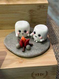 there are two small figurines sitting next to each other on top of a rock