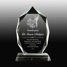 a clear glass award with a floral design on the front and bottom, along with a black background