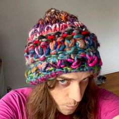 a man with long hair wearing a multicolored knitted hat on his head